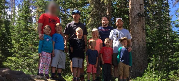 Dad Camp 2017 group photo: dads and kids standing together among tall pine trees, Grandaddy Lake trip